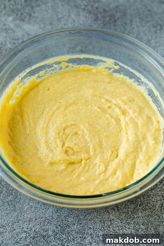Homemade corn dogs are so easy to make and are even better than what you'd get at the fair! A close-up shot of a bowl filled with smooth, golden cornbread batter, ready for dipping, showcasing its perfect consistency.