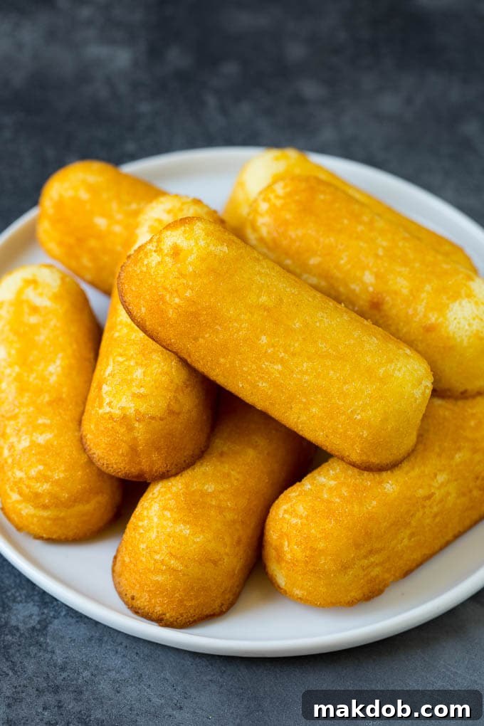 Fried Twinkies are a remake of the carnival classic that are fun and easy to make at home. A plate with a pile of Twinkies on it.