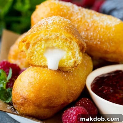 A plate of perfectly golden-brown fried Twinkies, artfully arranged and served with a small bowl of vibrant raspberry sauce. The image highlights the crispy exterior and promises a delightful sweet treat.