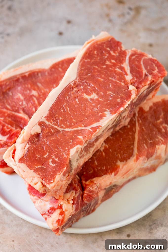 Seared New York strip steak with garlic and herb butter, an easy and elegant meal! Raw steaks on a plate.