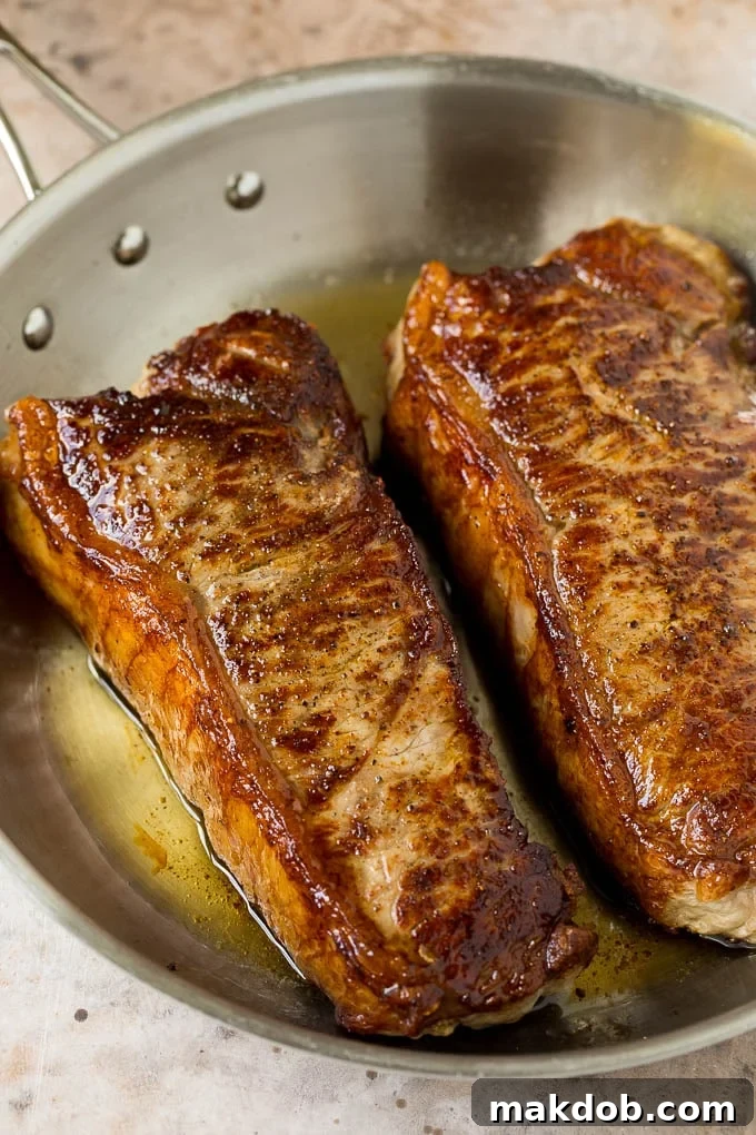 Seared New York strip steak with garlic and herb butter, an easy and elegant meal! Seared steaks in a skillet.