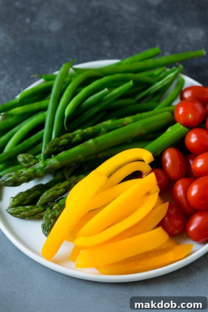 Colorful Bell Peppers, Asparagus, Tomatoes, and Green Beans for Your Veggie Platter An appetizing close-up of colorful bell peppers, tender asparagus spears, ripe cherry tomatoes, and crisp green beans artfully arranged on a white serving plate, showcasing fresh party vegetables.