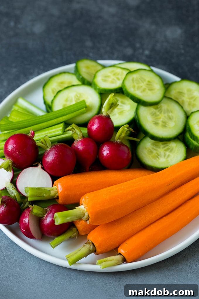 Carrots, Celery, Radishes, and Cucumber: Essential Veggies for Your Tray A fresh and crisp assortment of carrots, celery sticks, vibrant radishes, and sliced cucumber arranged neatly on a white plate, highlighting a selection of classic crudité ingredients.