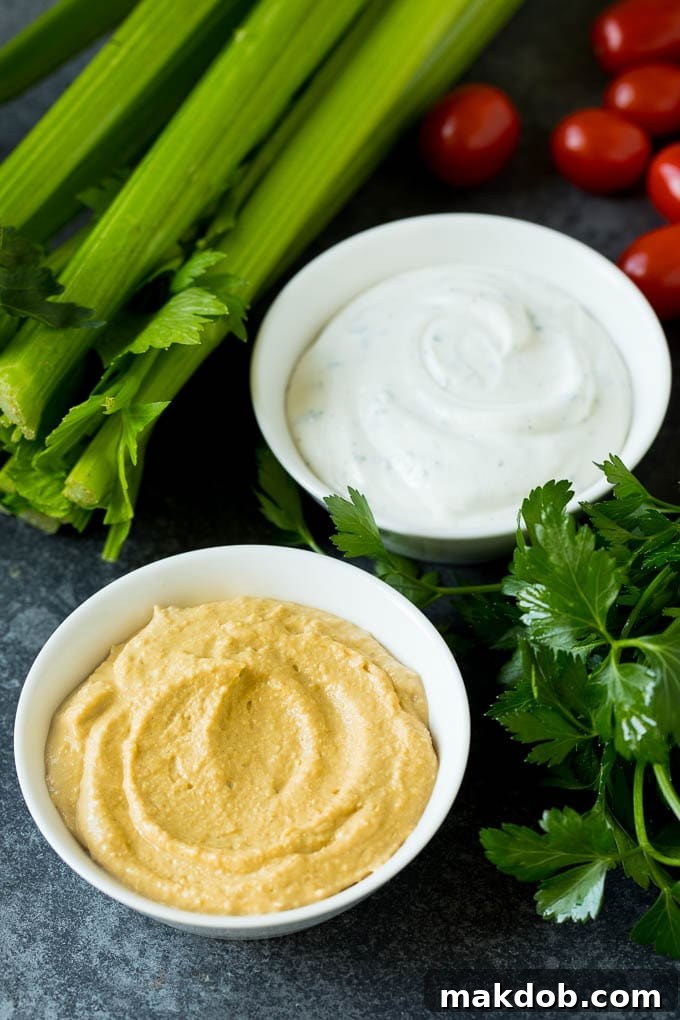 Creamy Hummus and Classic Ranch Dip for Your Veggie Platter Two ceramic bowls filled with creamy hummus and rich ranch dip, ready to accompany a vegetable platter.