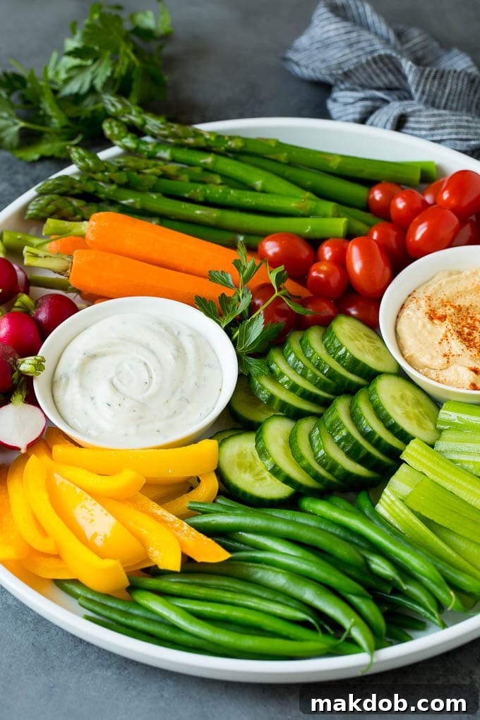 A Vibrant Veggie Tray with Fresh Vegetables and Two Dips An abundant veggie tray generously filled with a variety of fresh, colorful vegetables and two distinct bowls of delicious dips, perfectly arranged for serving.