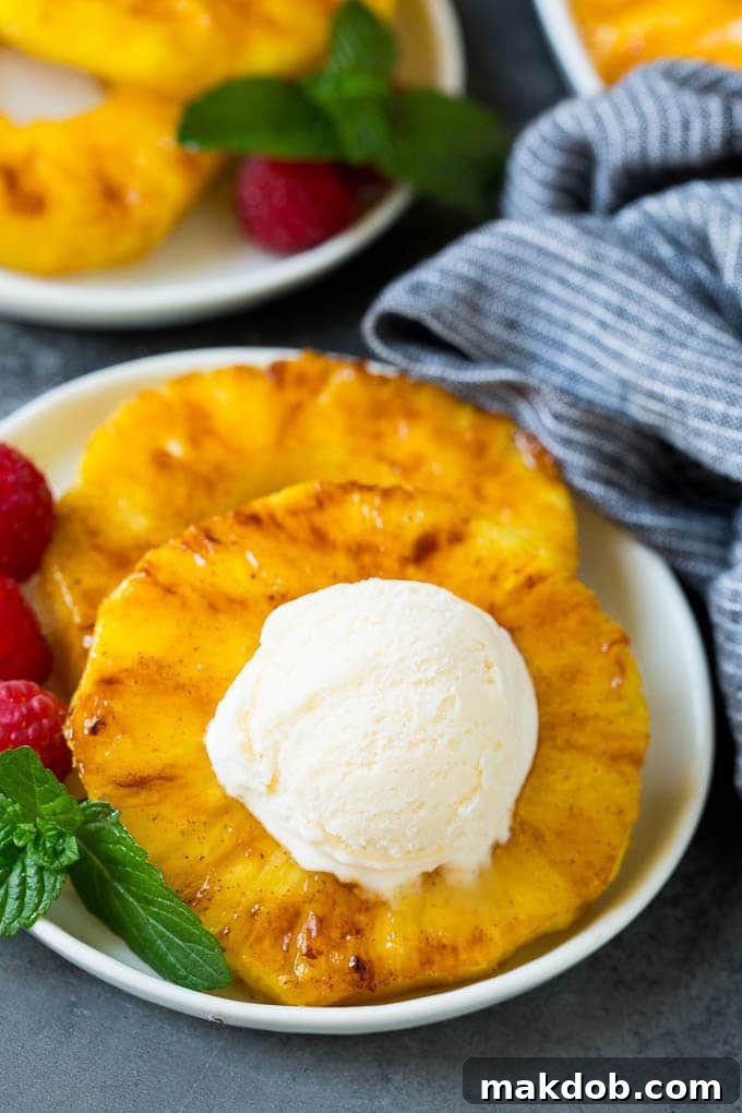 Grilled pineapple served with a scoop of vanilla ice cream and a drizzle of caramel sauce, a perfect summer dessert.