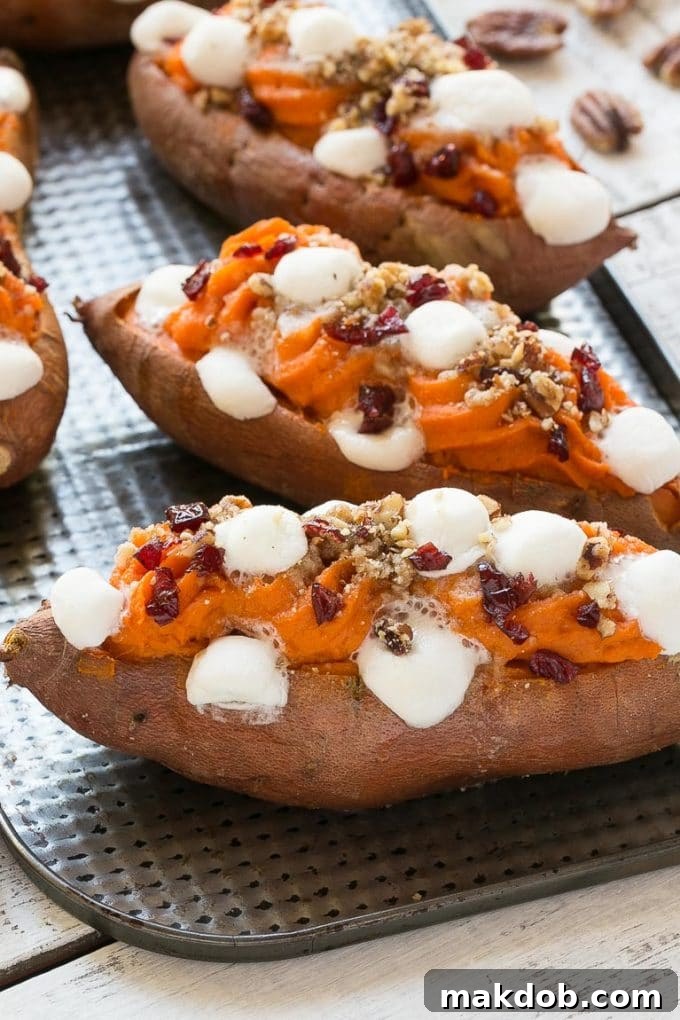Expertly cooked sweet potatoes on a baking tray, showcasing their tender flesh and a layer of perfectly melted mini marshmallows, ready for the next step of topping.