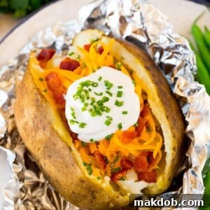 Fluffy crock pot baked potatoes, generously topped with creamy sour cream and crispy bacon bits.