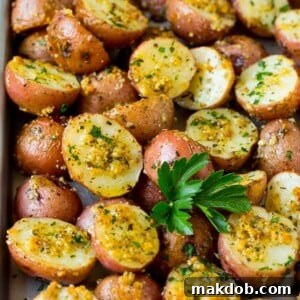 Golden oven-roasted potatoes, beautifully coated in aromatic garlic and herbs, and elegantly garnished with fresh parsley.