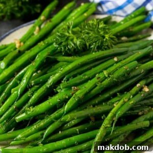 A plate of perfectly sautéed green beans, elegantly garnished with fresh parsley.