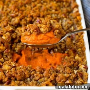 A spoonful serving a portion of luscious sweet potato souffle, showcasing its rich texture and streusel topping.