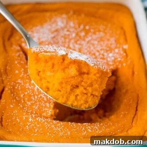 A spoon serving up a portion of light and fluffy carrot souffle, perfect as a versatile side or sweet treat.