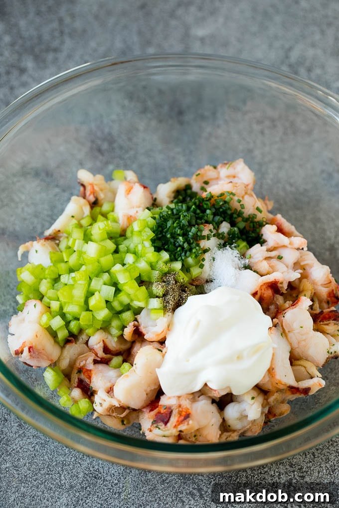 Lobster Salad Ingredients Ready to Mix A bowl filled with diced lobster, finely chopped celery, creamy mayonnaise, and fresh chives, ready to be mixed into a delectable salad.