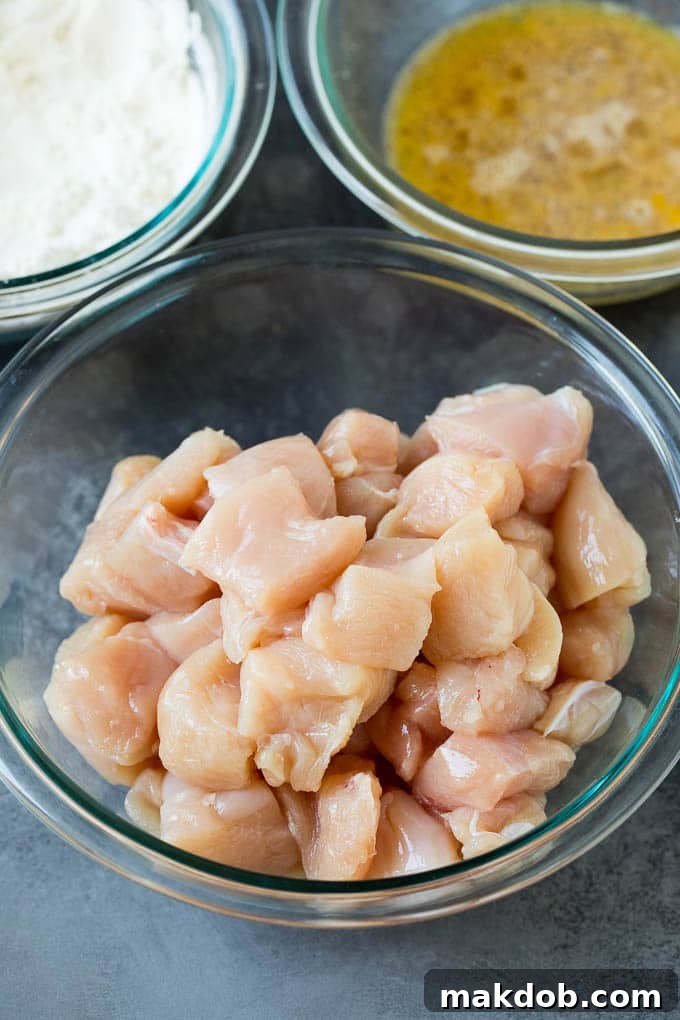 Honey Chicken Ingredients Preparation Bowls of diced chicken, beaten eggs, and flour mixture, prepared for coating.