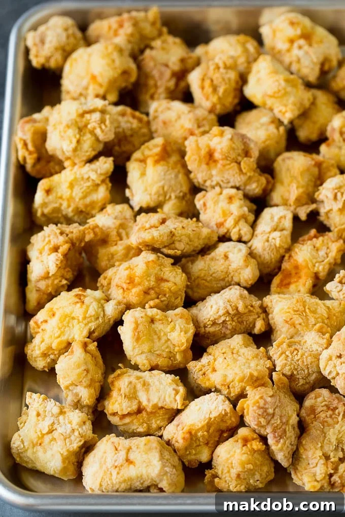 Crispy Fried Chicken Pieces Deep fried golden-brown chicken pieces resting on a sheet pan after cooking.