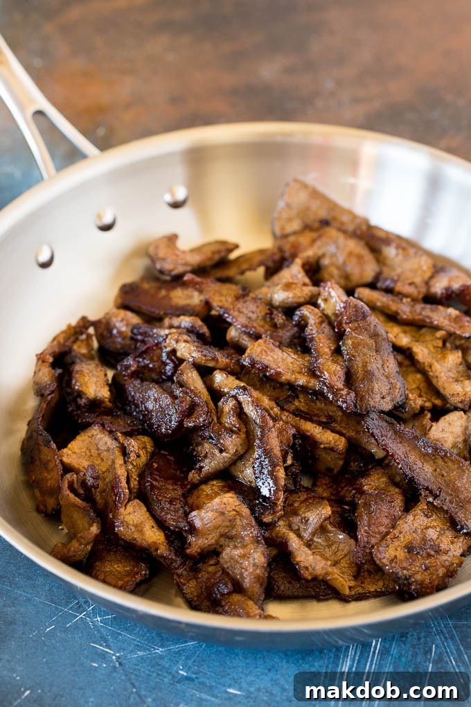 Perfectly seared flank steak glistening in a hot skillet, ready to be tossed into the lo mein for rich flavor and tender texture.