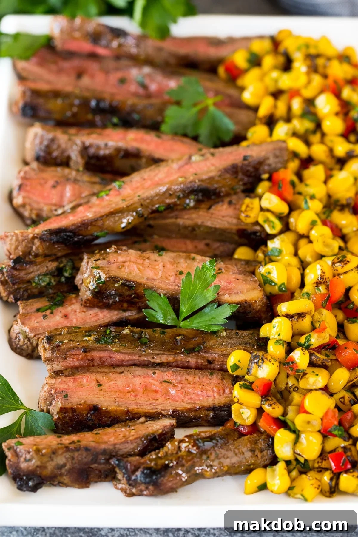 Perfectly sliced grilled flank steak arranged on a platter, ready to serve.