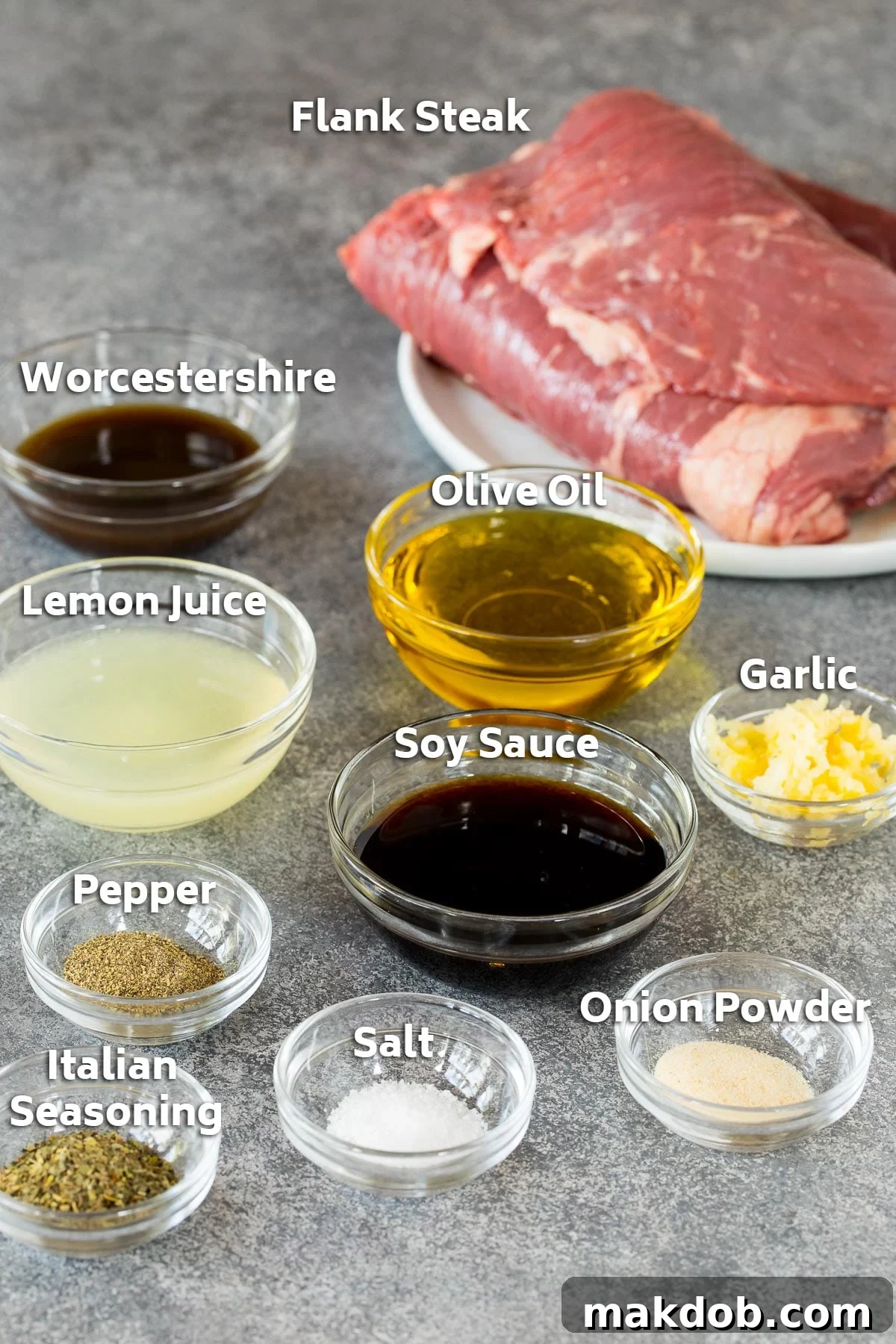 Bowls of soy sauce, lemon juice, olive oil, and spices laid out with a plate of raw flank steak, showing marinade ingredients.