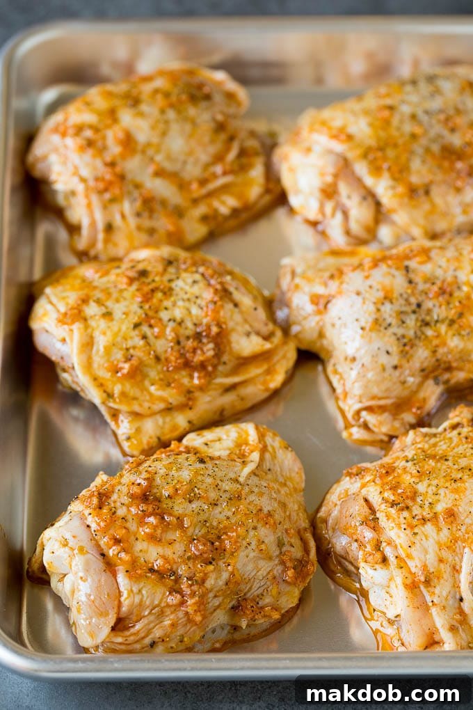 These baked chicken thighs are coated in olive oil, garlic and herbs, then oven roasted until golden brown. Marinated chicken thighs on a sheet pan.