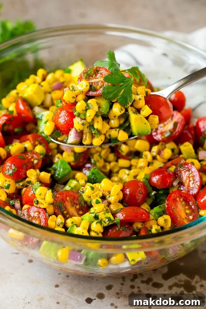 A spoon serving up a portion of corn salad.