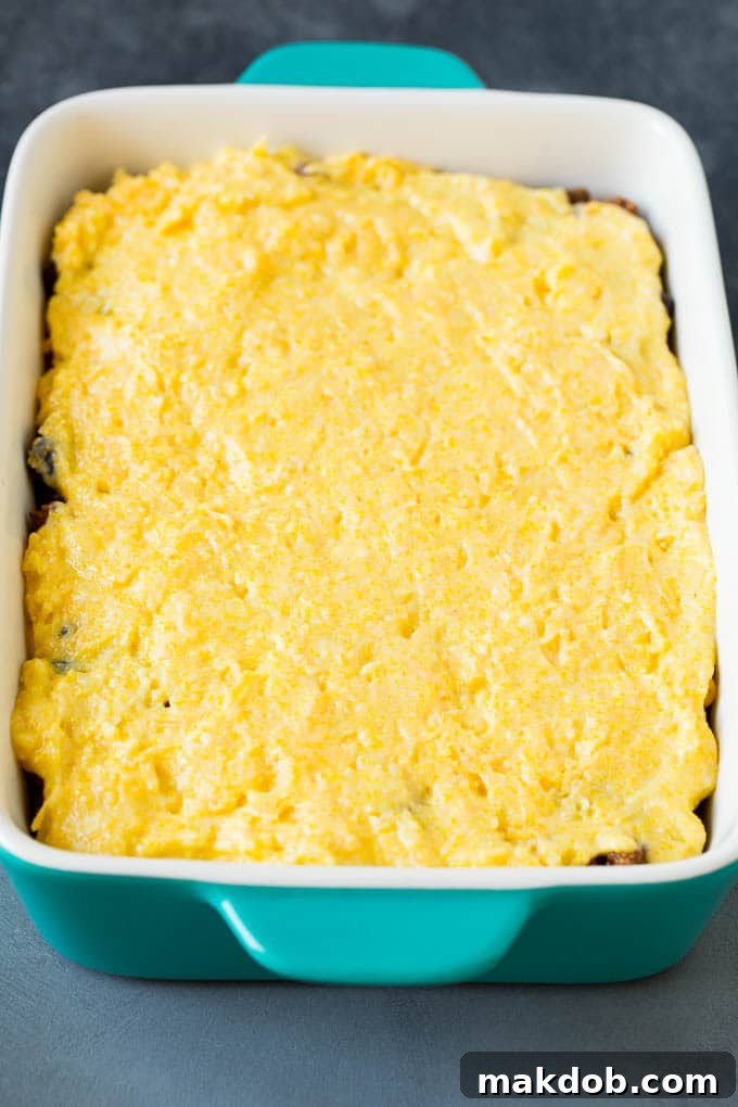Beef in a casserole dish with a cornbread batter on top.
