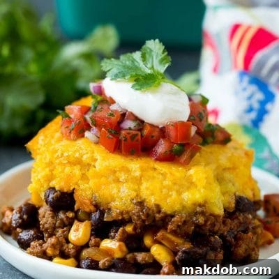 A slice of tamale pie topped with salsa and sour cream.