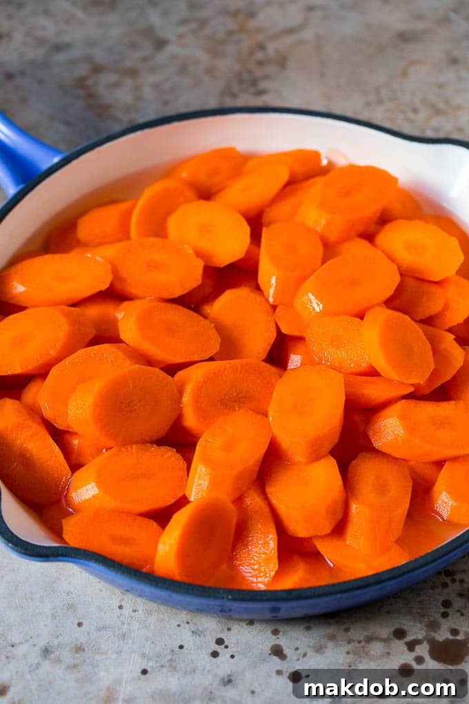Sliced carrots cooked in water in a pan.