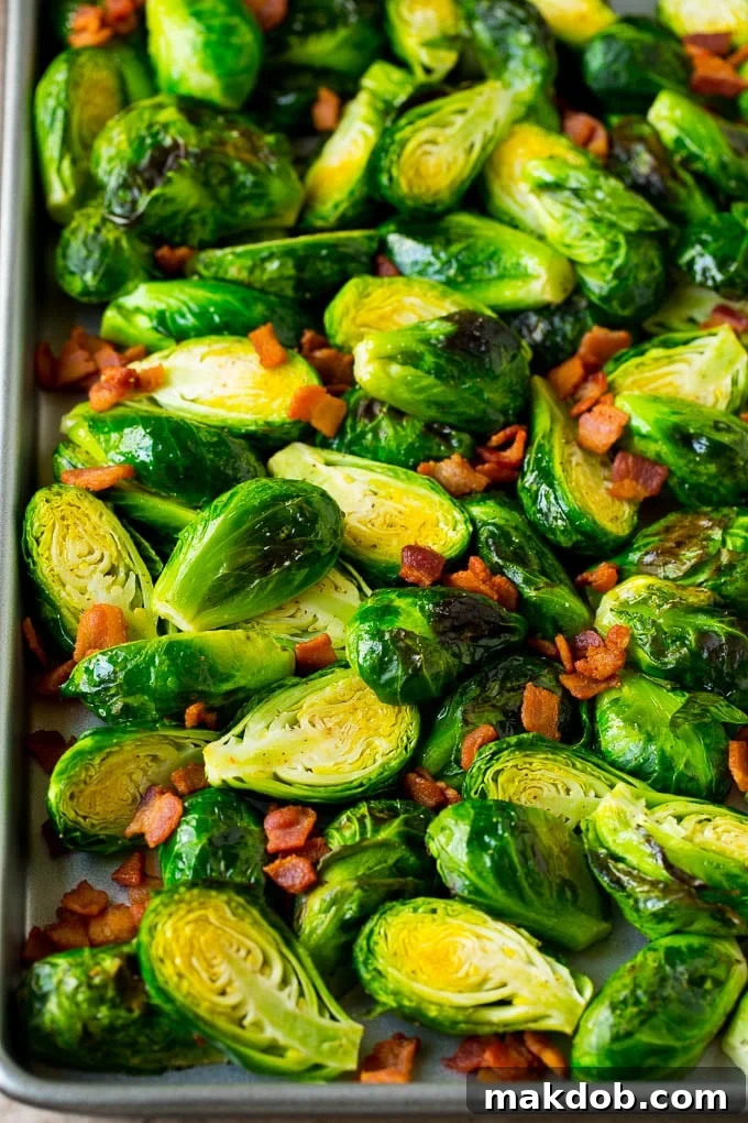Close-up of roasted brussels sprouts and crispy bacon on a sheet pan.