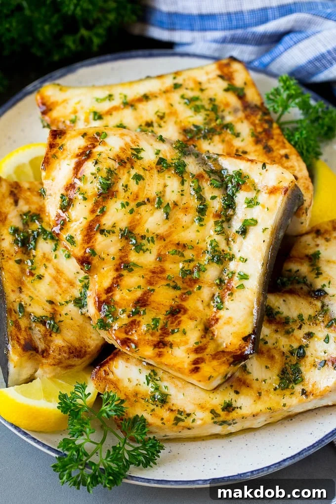 A plate of grilled swordfish steaks topped with herbs.