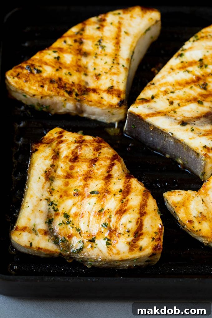 Swordfish steaks being cooked on an indoor grill pan, showing grill marks.
