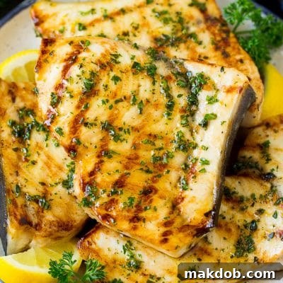 A plate of grilled swordfish steaks topped with herbs.