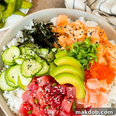 A sushi bowl topped with salmon, ahi, avocado, cucumber and nori.