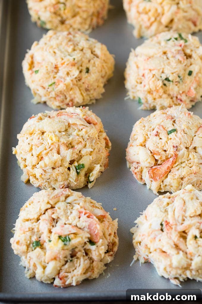 These Maryland crab cakes are fresh crab combined with seasonings and cracker crumbs, then baked to make an easy yet elegant appetizer or main course. Crab patties on a sheet pan.