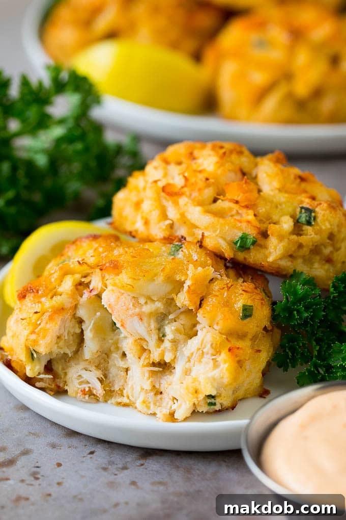 These Maryland crab cakes are fresh crab combined with seasonings and cracker crumbs, then baked to make an easy yet elegant appetizer or main course. A serving of Maryland crab cakes with a side of remoulade sauce.