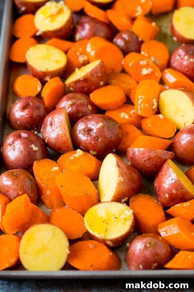 Vegetables spread out onto a sheet pan for baking.
