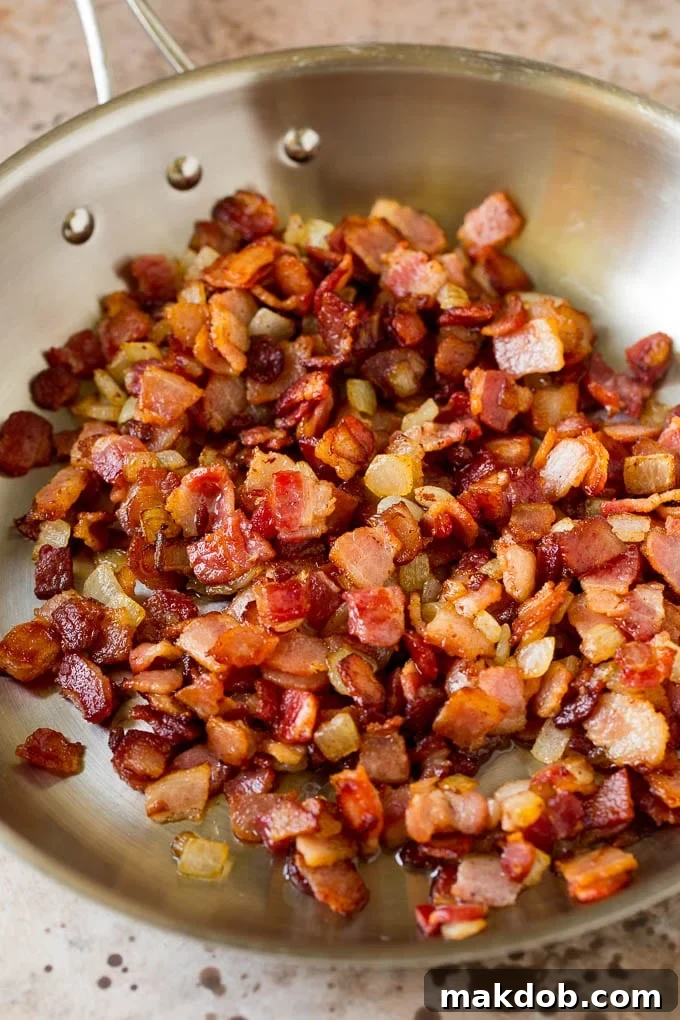 This German potato salad is boiled baby potatoes tossed in a warm bacon and mustard dressing, then garnished with fresh herbs. Bacon and onions cooked in a skillet.