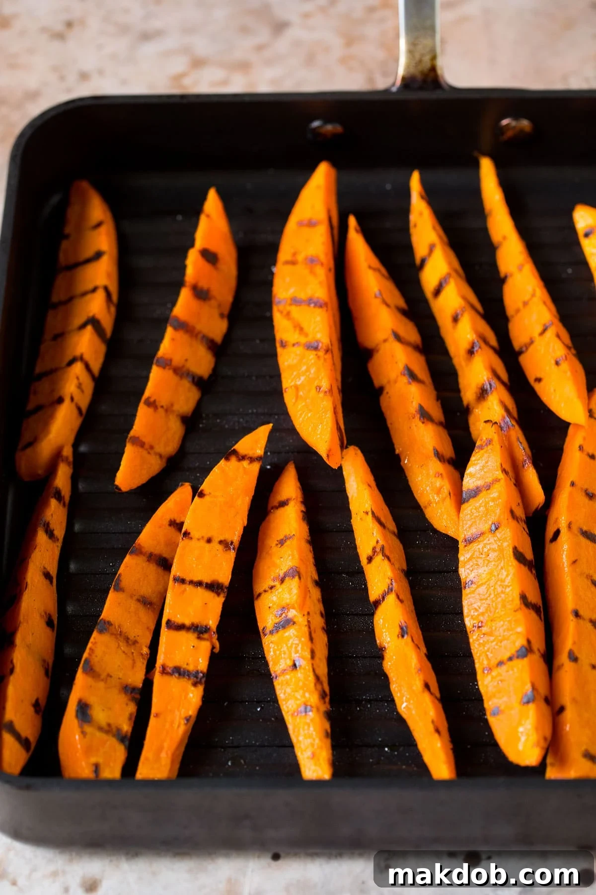 Fire-Kissed Sweet Potatoes 5 Sweet potato wedges cooked on an indoor grill pan, showing clear grill marks.