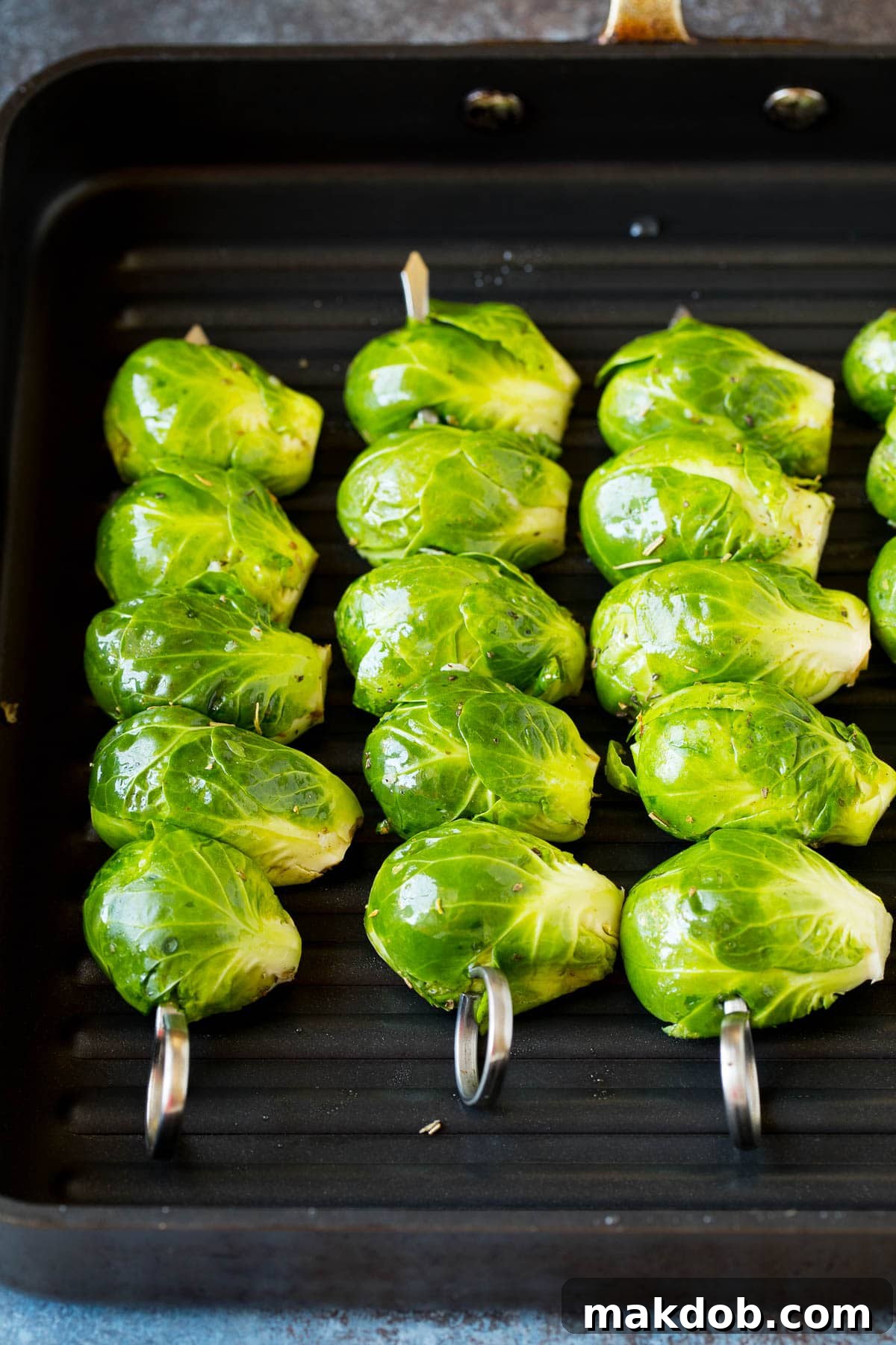 Flame-Kissed Brussels Sprouts 5 Brussels sprouts on skewers on a grill pan.