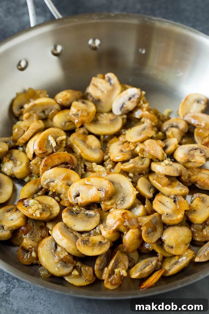 Freshly sautéed mushrooms and onions, ready for the next step in the casserole. Sauteed mushrooms and onions in a pan, cooked until tender and lightly browned.