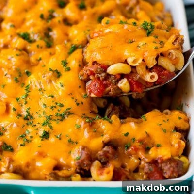 Cheeseburger Bake 2 A spoon serving up a portion of hamburger casserole made with pasta and melted cheese.