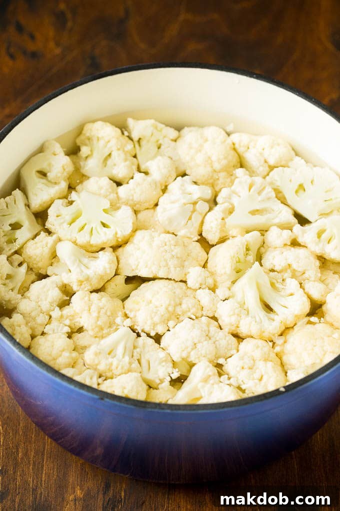 Cooking Cauliflower for Mashed Potatoes Cauliflower florets simmering in a pot of salted water, preparing for a creamy mashed cauliflower recipe.