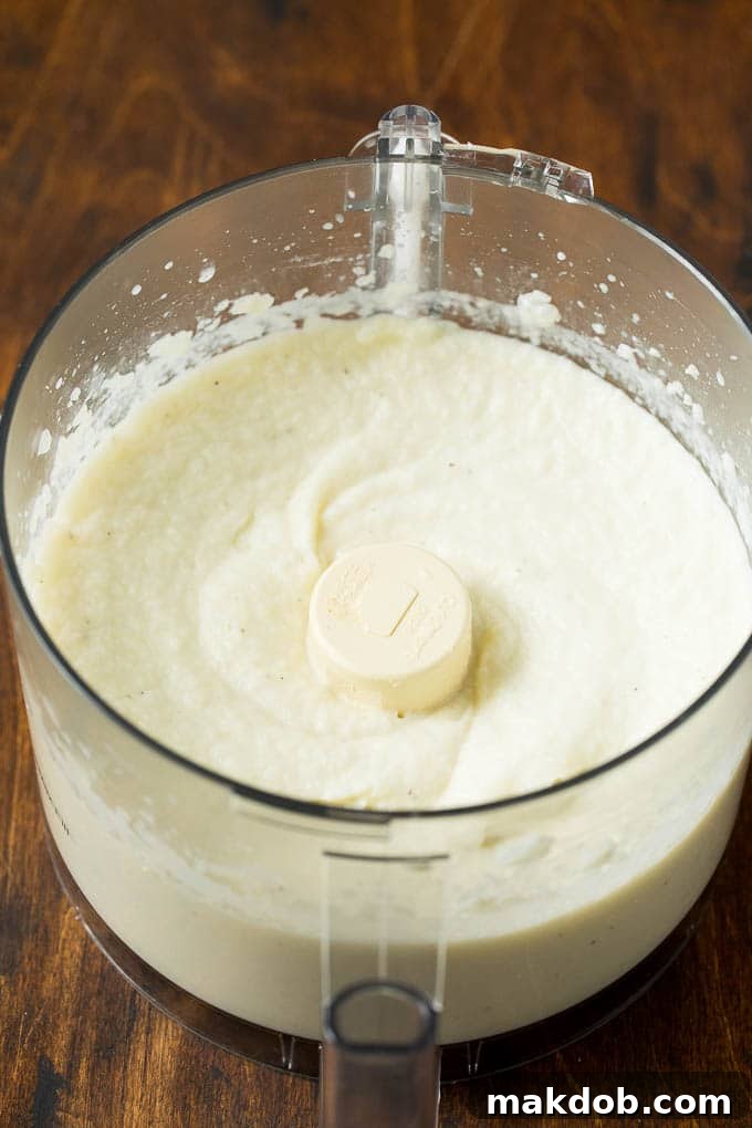 Achieving Smooth Mashed Cauliflower Smooth, creamy cauliflower puree in a food processor, ready to be seasoned and served.