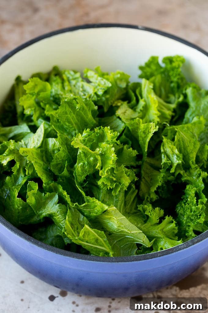 These Southern style mustard greens are cooked with smoky bacon and seasonings until tender and flavorful. Torn leafy vegetables in a pot with bacon and onions.