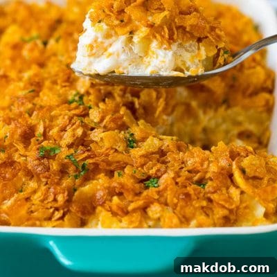 Ultimate Cheesy Potato Casserole 2 A spoon serving up a portion of cheesy funeral potatoes.