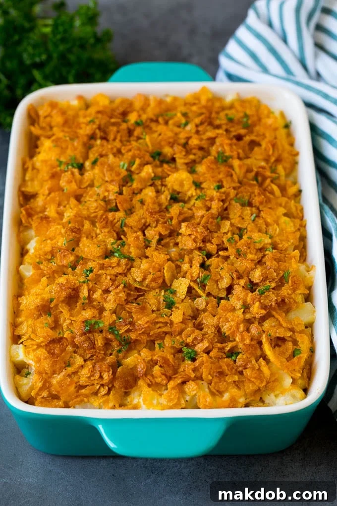 Funeral Potatoes, a creamy and cheesy casserole with a crispy topping. A close-up of a completed dish of funeral potatoes, generously topped with buttery cornflakes and sprinkled with fresh green parsley, ready for serving.