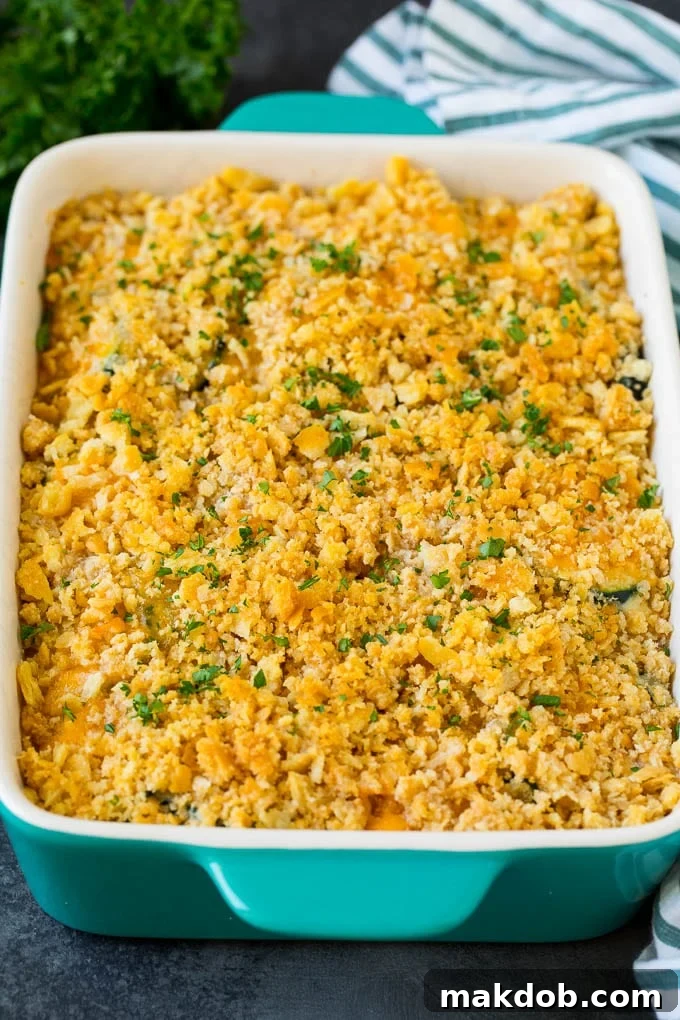 A baking dish with creamy zucchini casserole topped with crushed cracker crumbs, ready for the oven.