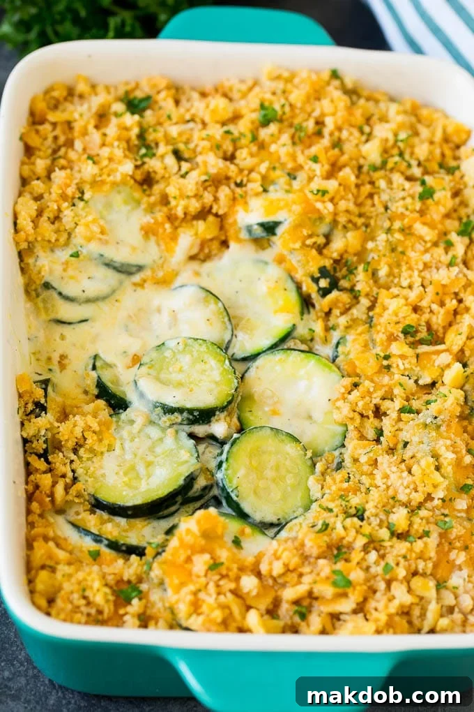 A fully baked zucchini casserole with sliced squash in a creamy sauce, topped with melted cheese and golden-brown cracker crumbs.