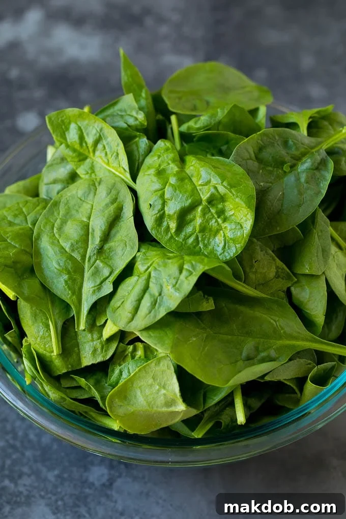 A bowl of fresh, vibrant baby spinach leaves, ready for cooking.