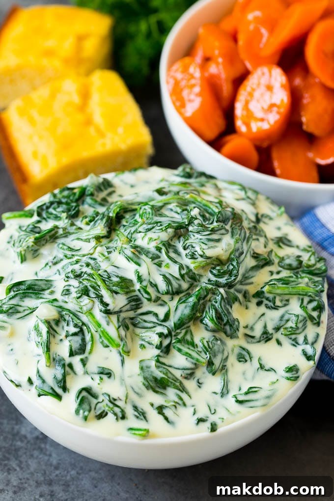 A beautifully arranged serving of creamed spinach, accompanied by glazed carrots and cornbread, showcasing its versatility as a side dish.