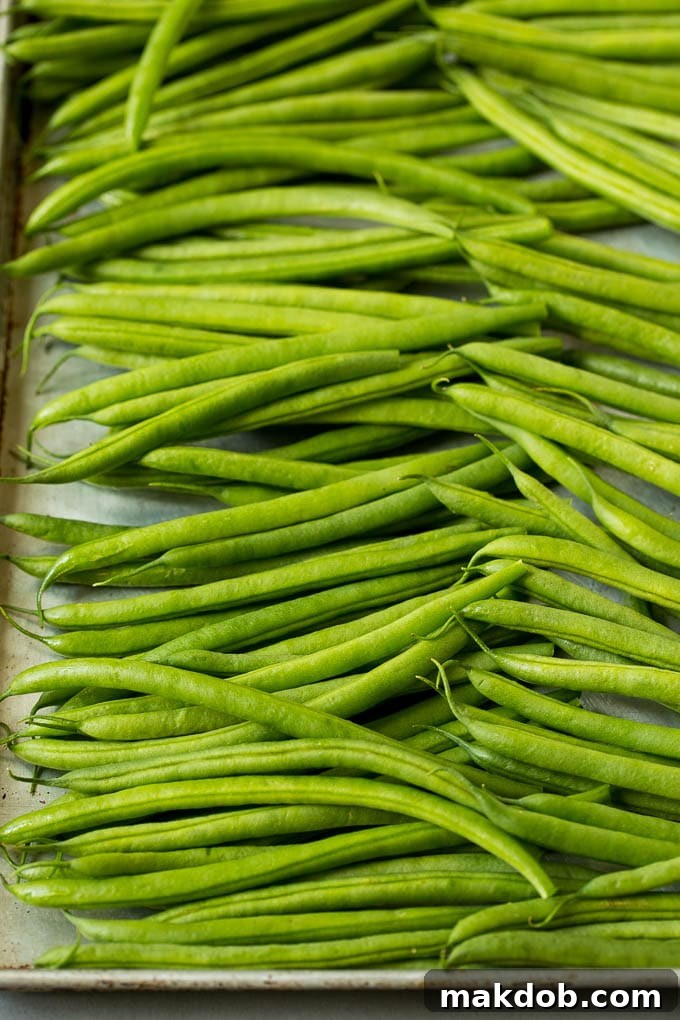 These sauteed green beans are cooked in butter, garlic and an assortment of fresh and dried herbs. Raw green beans on a sheet pan.